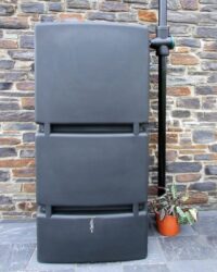 grote zwarte regenton aan regenpijp tegen stenen muur