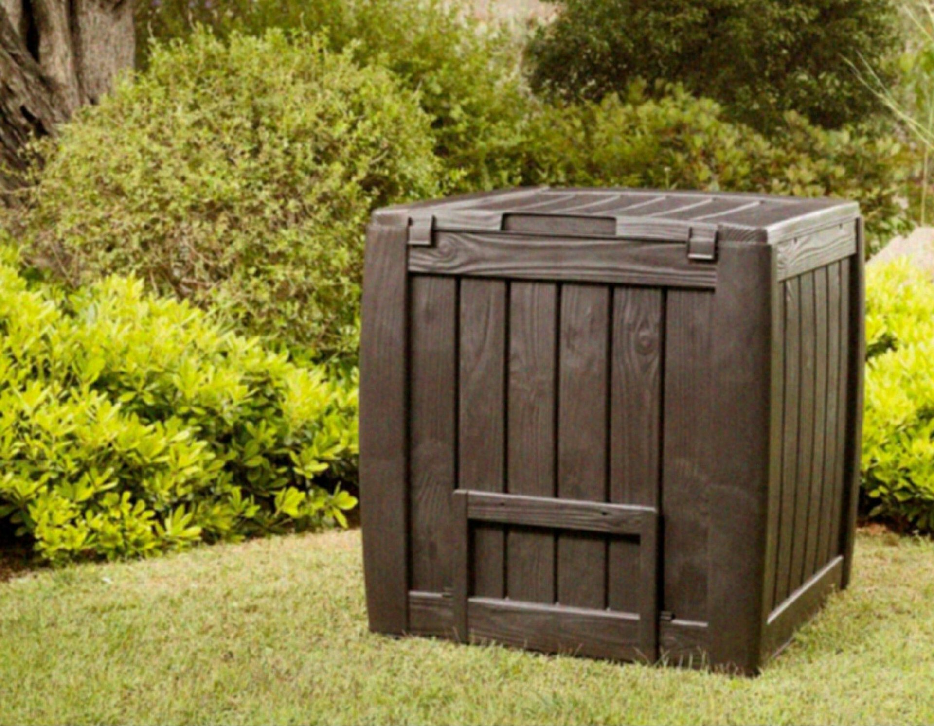 compostbak die op een houten kist lijkt in een tuin op het gras