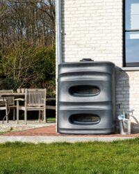 zwarte regenton met uniek design in de tuin tegen de muur
