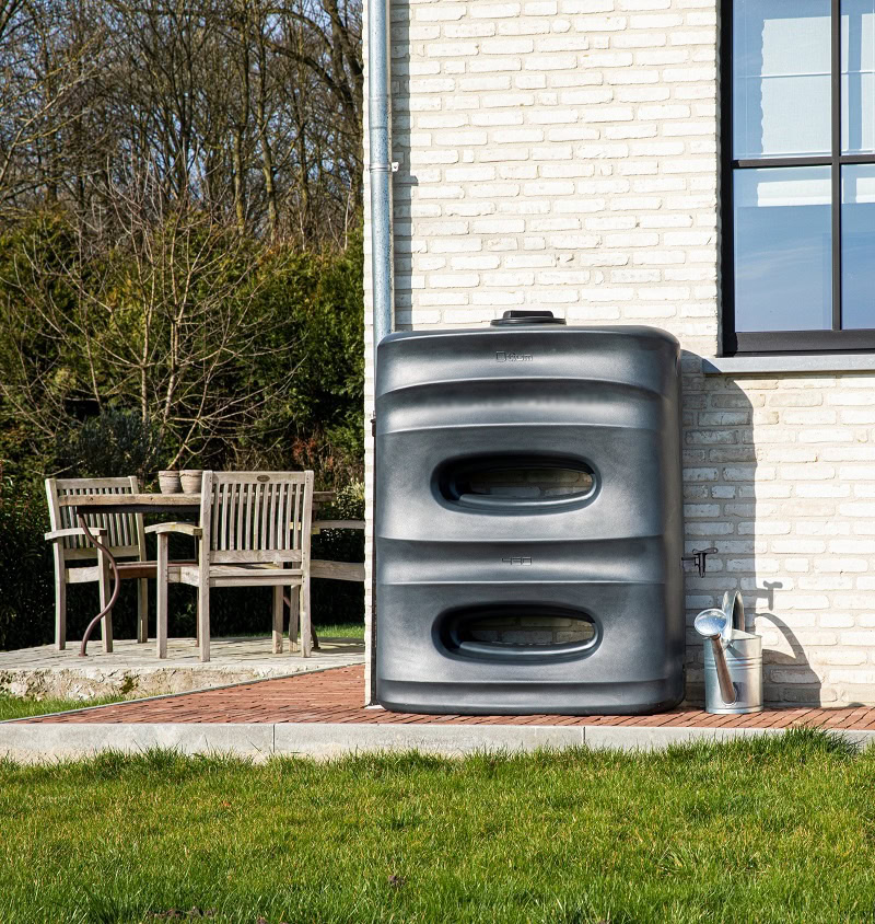 zwarte regenton met uniek design in de tuin tegen de muur